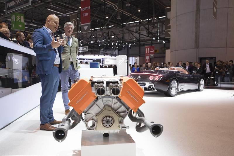 Koenigsegg speaks on his engine while Spyker head Victor Muller watches, his new car in the background. Photo Credit: Spyker